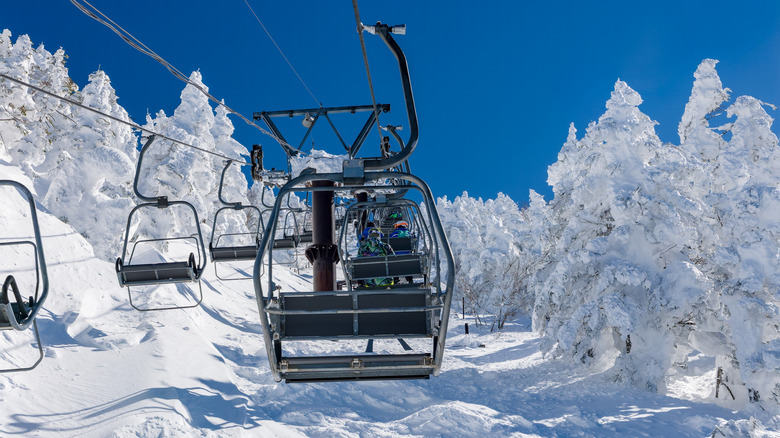 First person view from a chairlift ascending a snowy mountain at a ski resort in Japan.