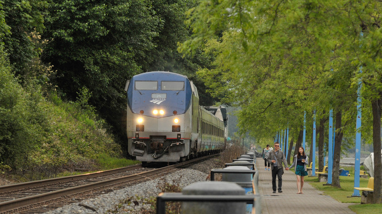 Couple walking by the train tracks as a train goes by