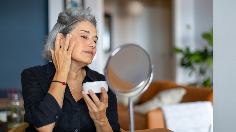 woman putting on moisturizer