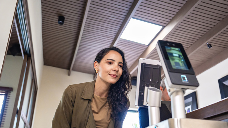 Woman using a biometric facial recognition access at a security checkpoint