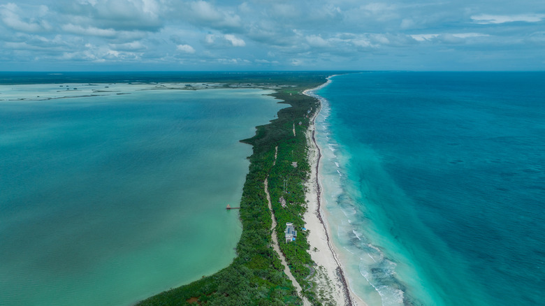 An aerial view of the thin strip of beach and jungle surrounded by the sea and lagoon in the Sian Kaʼan Biosphere.