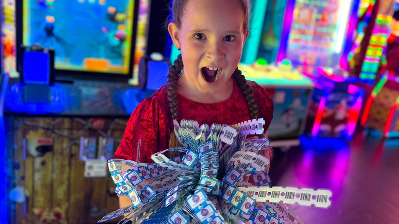 girl holding a lot of arcade tickets