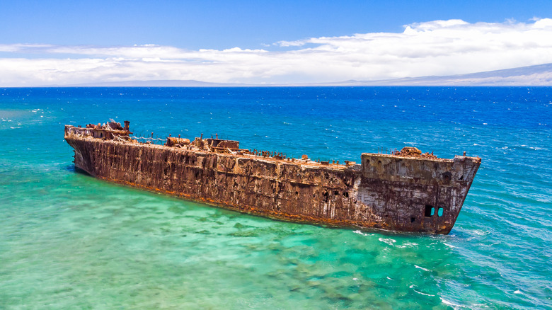 A rusty shipwreck in turquoise water off the coast of Shipwreck Beach on the island of Lanai