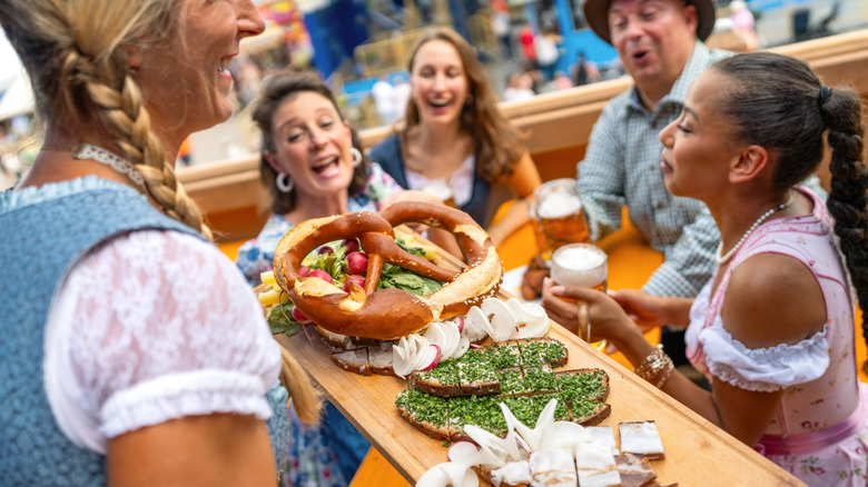 Waitress serves traditional German food to a group of laughing friends at Oktoberfest in Munich