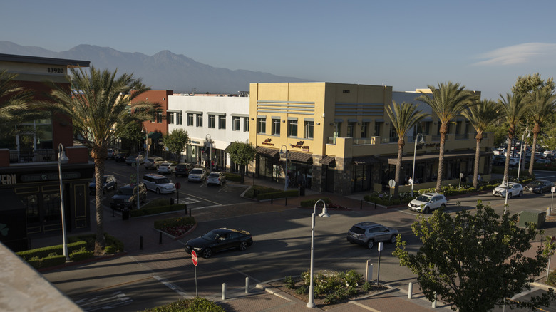 Cars driving past restaurants, shops, and palm trees in downtown Chino Hills, California