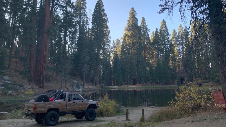 Camoflauged car near Hedrick pond with water and tall trees