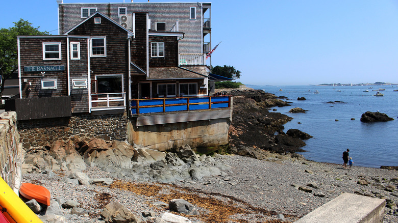 A small rocky beach with the Barnacle restaurant in the background