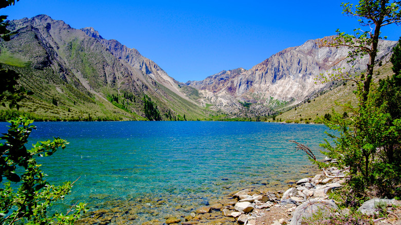 A crystal blue lake surrounded by mountains and green trees